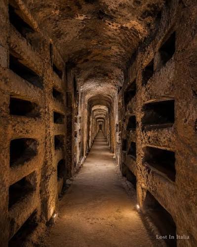 Candlelit stone tunnel of the ancient Roman catacombs
