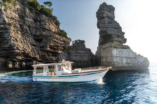 Colorful fishing boats moored in a turquoise Positano cove, cliffs above