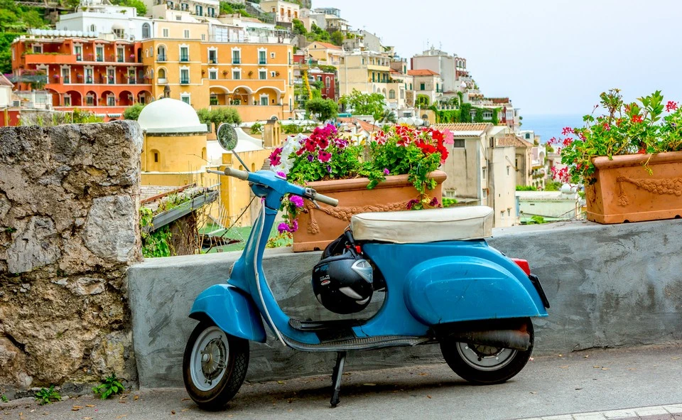 A Vespa scooter parked on a coastal road overlooking the Sorrento cliffs